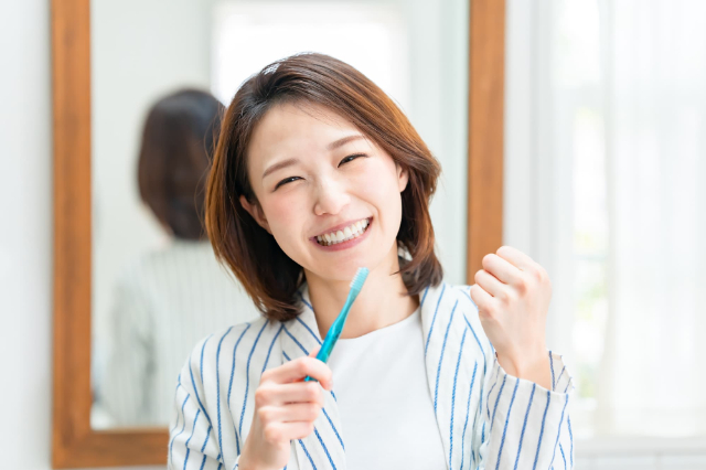 歯ブラシを持って笑顔でガッツポーズする女性