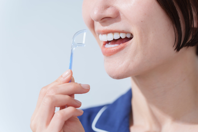 デンタルフロスを嗅いで自分に口臭があるか確認しているイメージ