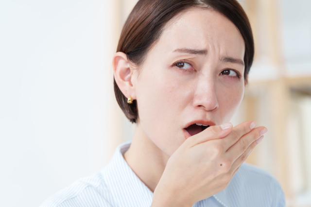 口臭が気になって息を確認する女性