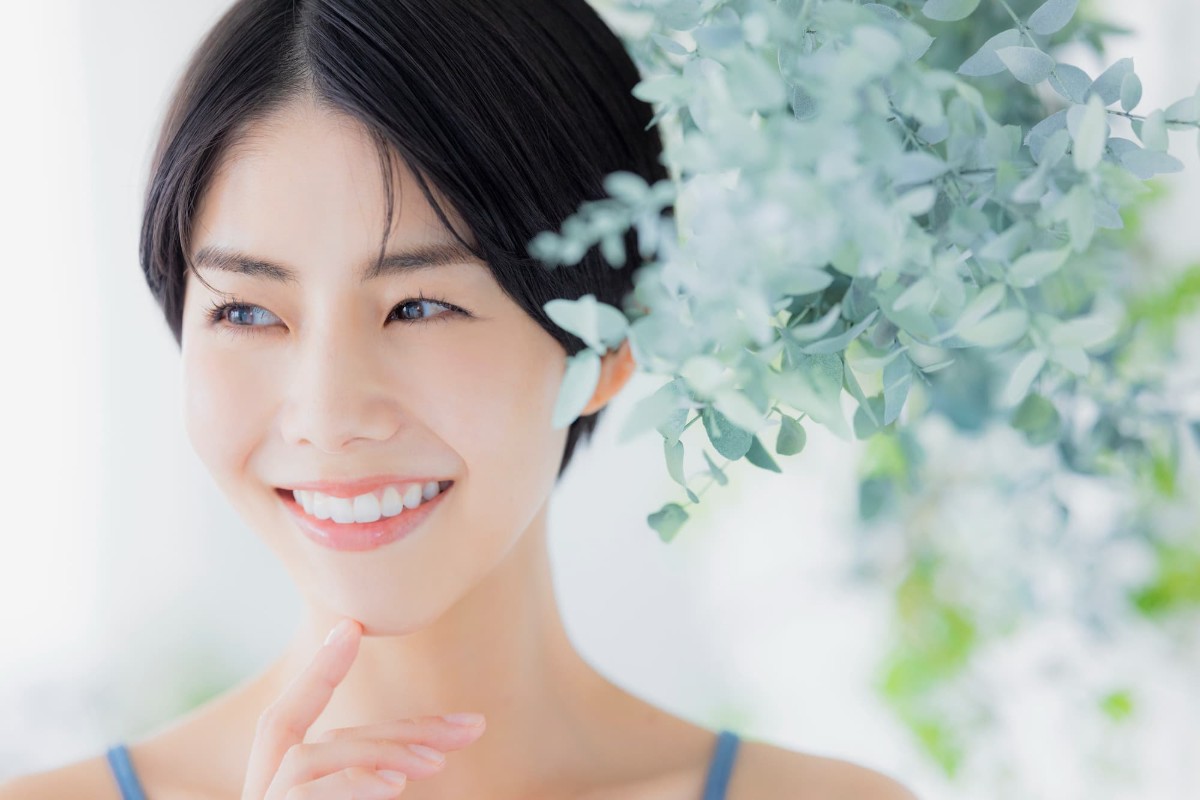 ホワイトニングをした白い歯に満足して微笑む女性
