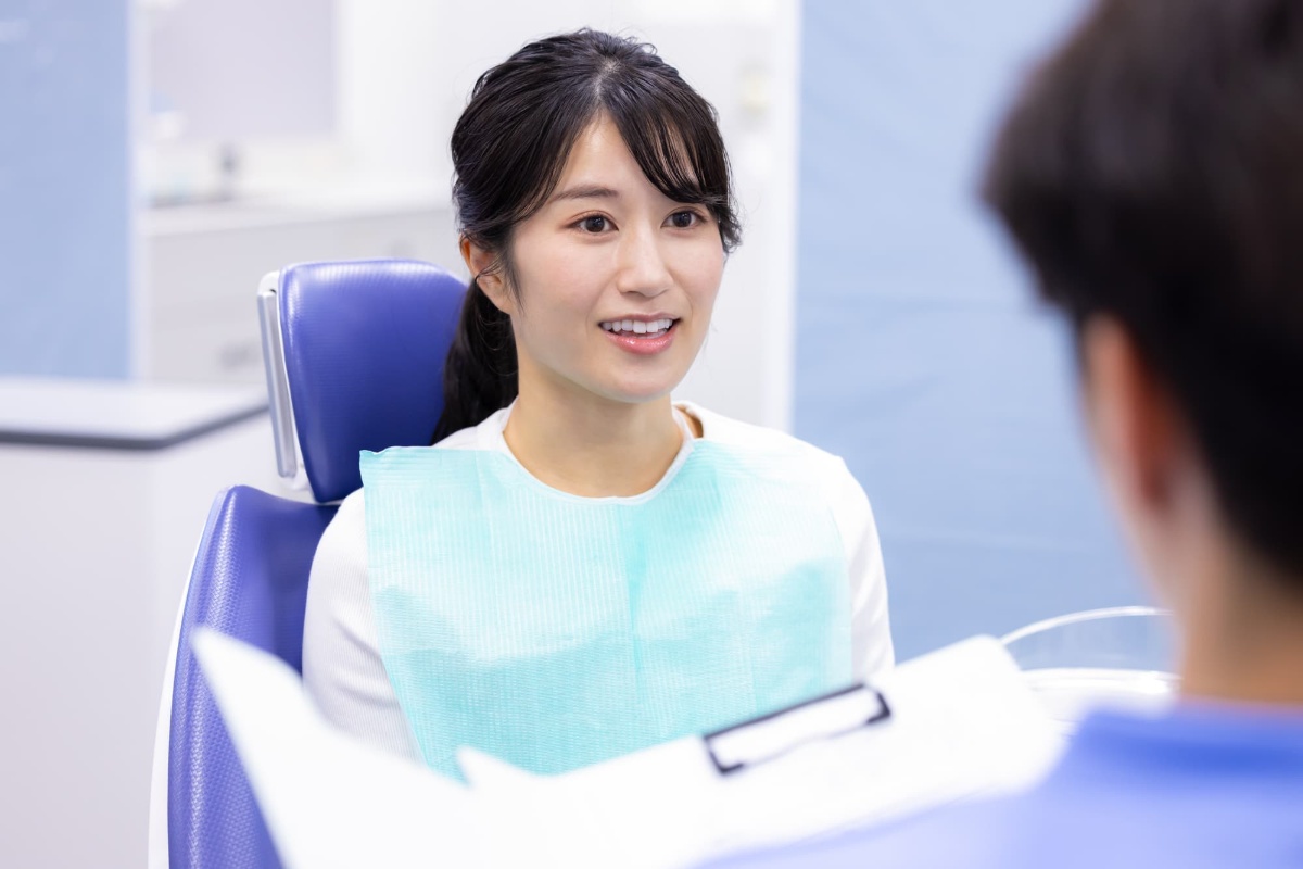 ホワイトニング後に歯がしみる女性が歯科医に相談するイメージ