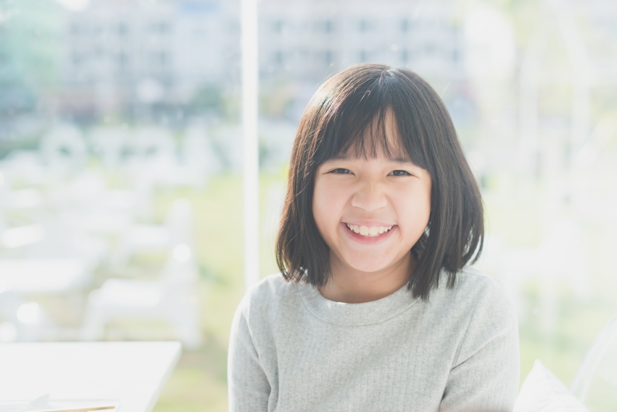 後戻りを起こさずに矯正後の整った歯並びを維持している笑顔の子ども